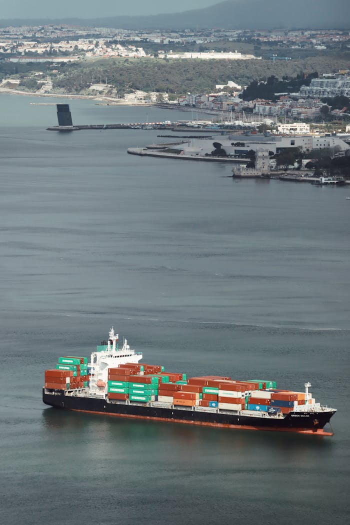 Aerial view of a container ship navigating Lisbon Harbor, showcasing cargo transport.