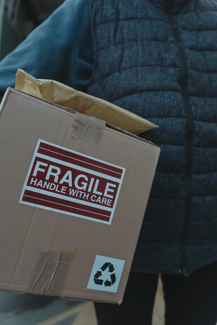 Close-up of a fragile package with care labels being handled by a person.