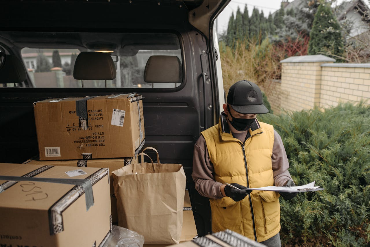 Delivery worker checks documents among packages in a van.